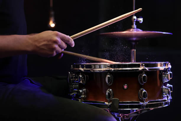 Drummer playing snare drum with sticks close up. Drum sticks hitting snare drum with splashing water on black background under studio lighting close up. drummer hands stock pictures, royalty-free photos & images