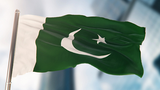 National Flag of Pakistan Against Defocused City Buildings