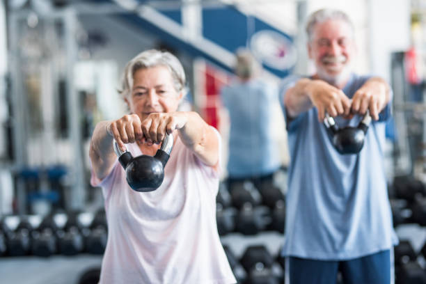 2人の幸せとフィットシニアのカップルは、一緒にタピスルーラントで走ってジムで運動をしている - アクティブなライフスタイル - gym weight bench exercising weights ストックフォトと画像