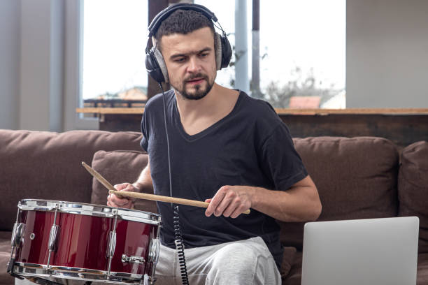 istock A young man with headphones learns to play the drum using online lessons. 1293496481