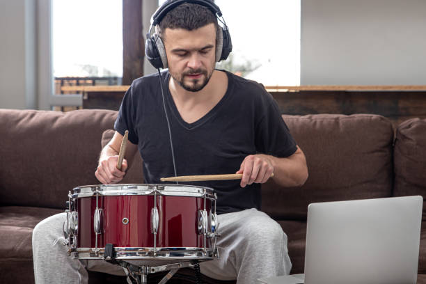 istock A young man with headphones learns to play the drum using online lessons. 1293496485