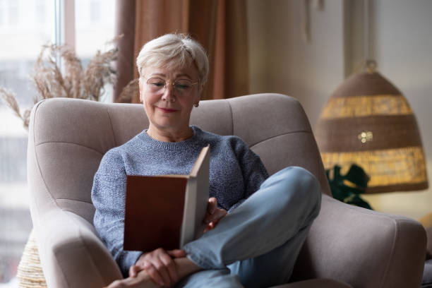 istock Senior caucasian woman at home reading book 1293500108