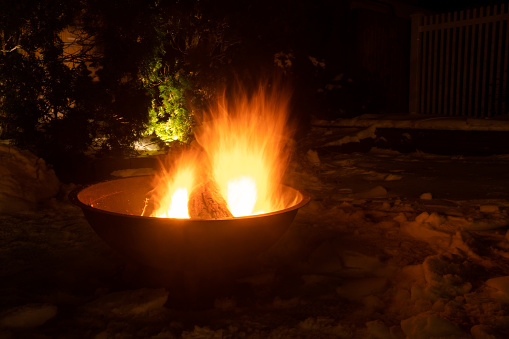 Atlantic Highlands, NJ, USA:    A fire burns in an outdoor fire pit on a snowy winter night