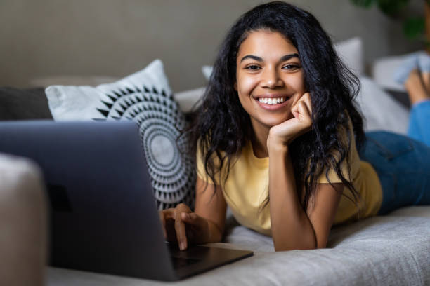 istock Beautiful young woman on a couch working with a laptop 1293501096