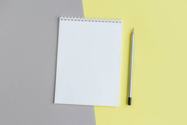 istock Notebook with blank page and pencil on a yellow and grey background. 1293505751