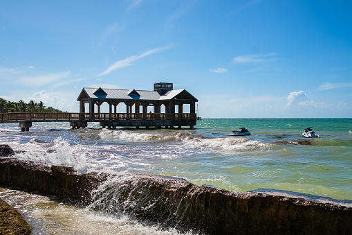 Beautiful Key West shoreline with a pier and waves splashing over the seawall.
