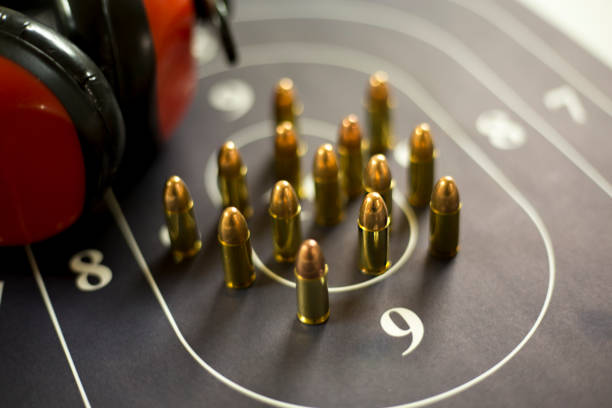 gun range earmuffs and ammunition on shooting target in display case. - full metal jacket imagens e fotografias de stock