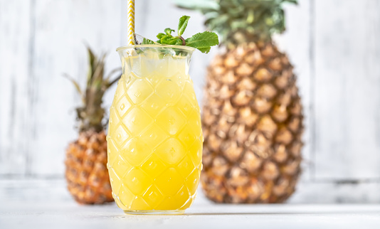 Glass of pineapple tiki style cocktail on white background