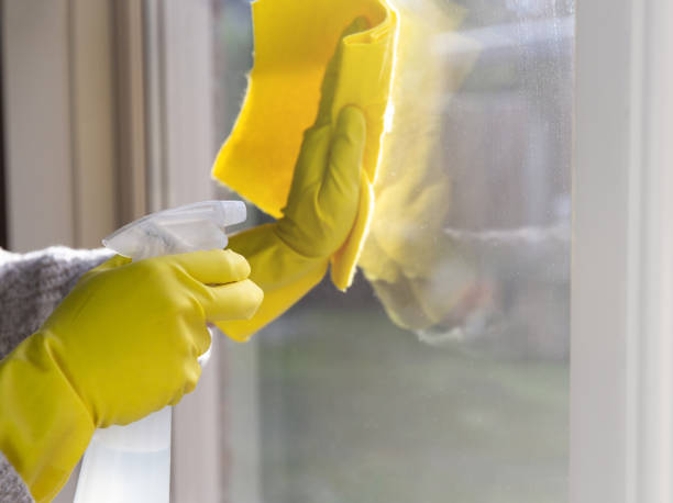 istock Cleaning a window with spray detergent, Yellow rubber gloves and dish cloth on work surface concept for hygiene, business and health concept 1293513930
