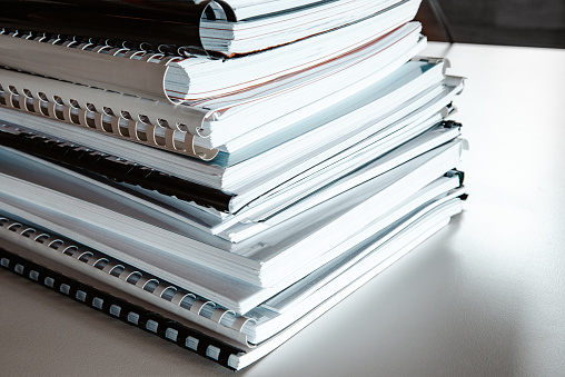Stack of reports lies on a desk ready for review and editing