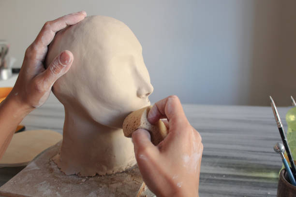 retouching handmade clay sculpture with wet sponge - sculpture clay human face human head imagens e fotografias de stock