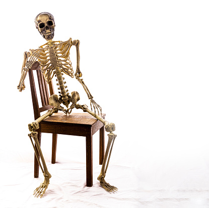 Skeleton on a chair in a studio, high key processed