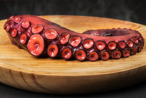 Freshly cooked octopus served on a wooden plate, a traditional Galician dish called \