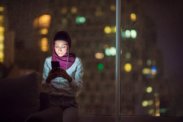 istock Young Muslim woman using her phone at night 1293536841