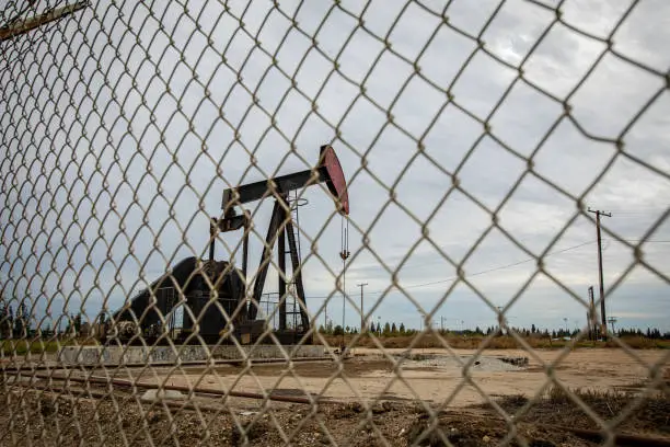 Photo of Oil Pump in Cloudy Rough Weather with Chain Link Fence