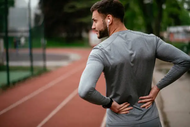 Photo of Sportsman suffering from backache at park outdoors