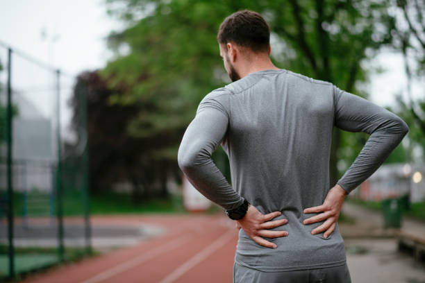 Sportsman suffering from backache at park outdoors Sportsman suffering from backache at park outdoors. Back Pain. Sport injury lower back pain stock pictures, royalty-free photos & images