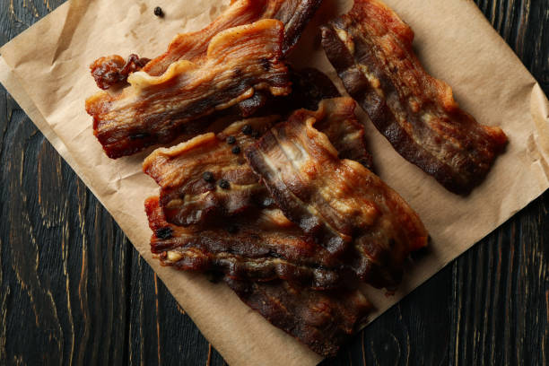 istock Baking paper with fried bacon on wooden background 1293559852