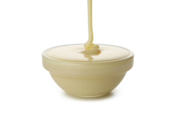istock Condensed milk pouring in bowl, isolated on white background 1293560123