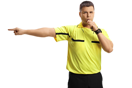 Football referee blowing a whistle and pointing isolated on white background