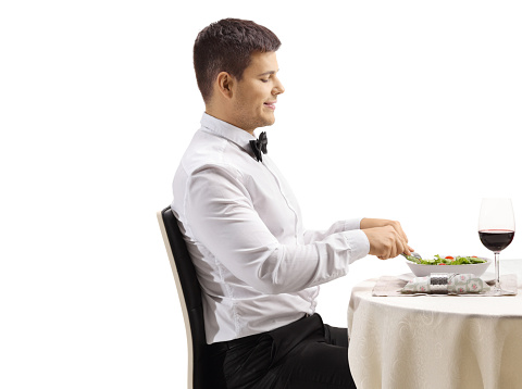Man eating a salad and at a restaurant table isolated on white background