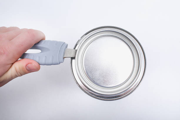 istock A man opens a jar of white paint with a can opener on a white background. Renovation 1293572292