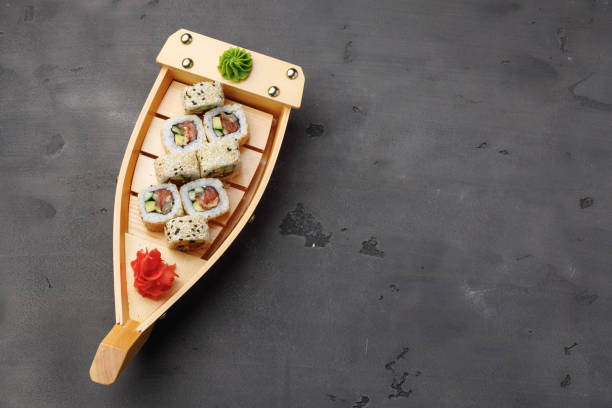 istock Sushi roll served on wooden boat plate on black background 1293574022