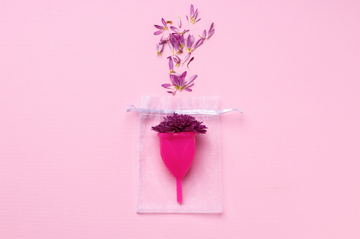 Copa menstrual con flores sobre fondo rosa photo