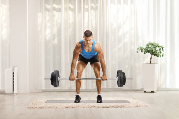 istock Young man lifting heavy weights and looking at camera at home 1293577104