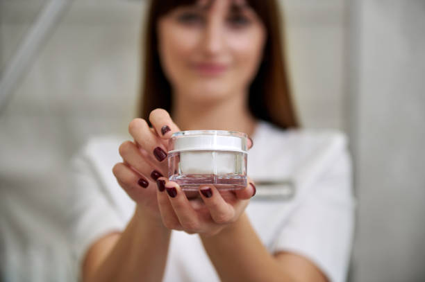 istock Selective focus of a bottle with moisurizing cream. A beautiful brunette holding a transparent bottle with cream. 1293579886
