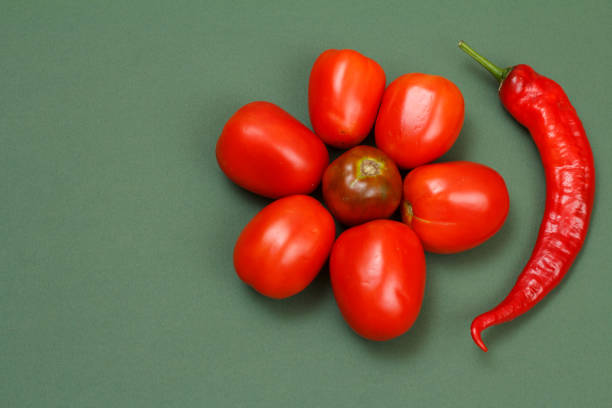 Top view of fresh tomatoes and ripe chili peppers on green color background. Vegetables on kitchen table. Top view.