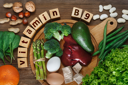 Foods rich in vitamin B9 (folic acid) as liver, asparagus, broccoli, eggs, salad, avocado, yeast, nuts, spinach, orange and beans. Top view