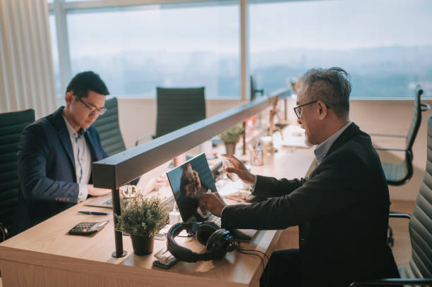 istock 2 asian chinese white collar worker at workstation working with new normal concept with Covid 19 disinfect their laptop 1293582919