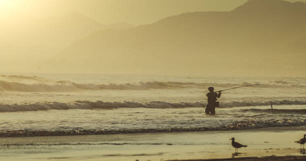 istock Man surf casting fishing in the Pacific Ocean 1293586389
