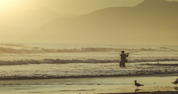 Man surf casting fishing in the Pacific Ocean