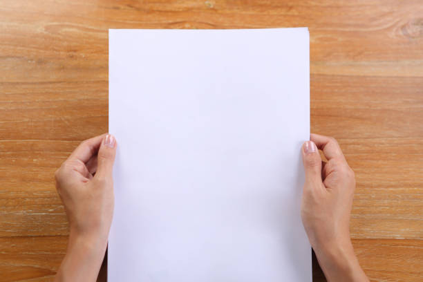 istock Top view hand holding A4 paper with wooden background 1293588257