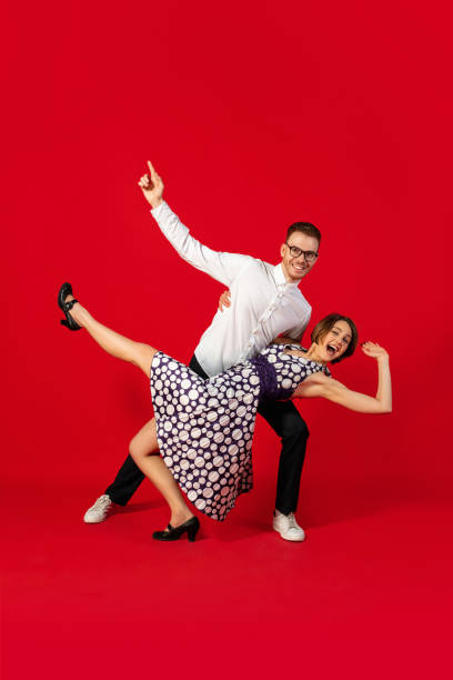 istock Old-school fashioned young couple dancing isolated on red background 1293588554