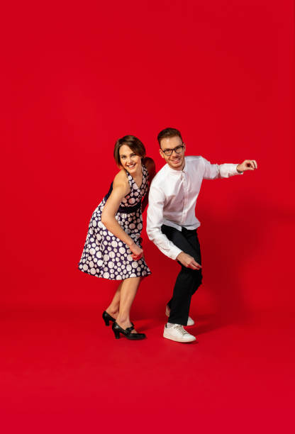 istock Old-school fashioned young couple dancing isolated on red background 1293588556