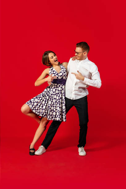 istock Old-school fashioned young couple dancing isolated on red background 1293588557