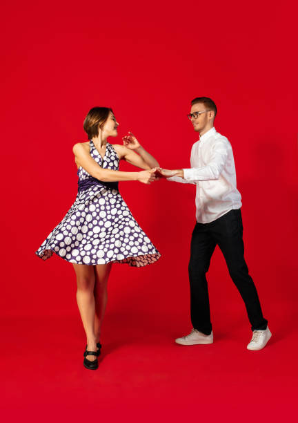 istock Old-school fashioned young couple dancing isolated on red background 1293588561