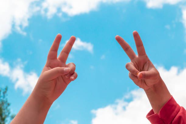 hands making the freedom sign with their hands raised to the sky