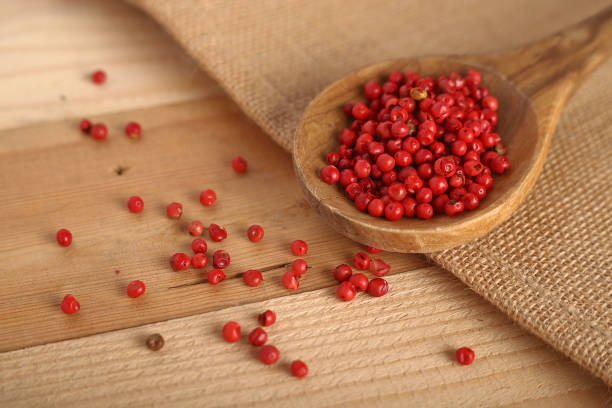 pink pepper balls in a wooden spoon - pink pepper imagens e fotografias de stock