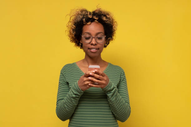 istock African young woman types text message on cell phone, enjoys online communication 1293591261