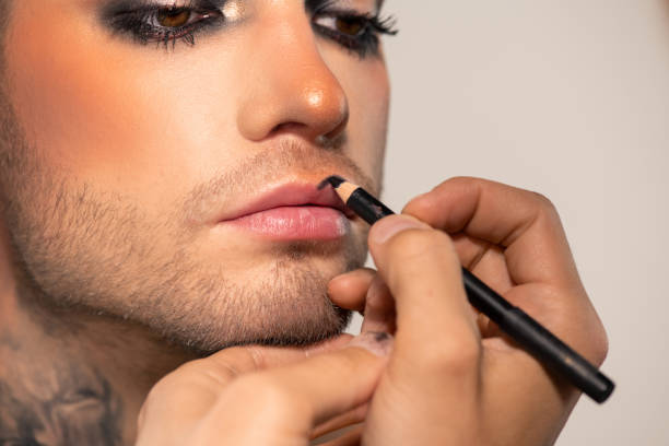 рука визажиста с черным колем накладыв его на губы мужской модели - human eye stage makeup male macro стоковые фото и изображения