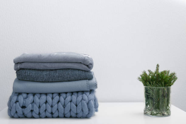 istock Stack of gray woolen knitted blankets and spruce fir tree branches 1293594338