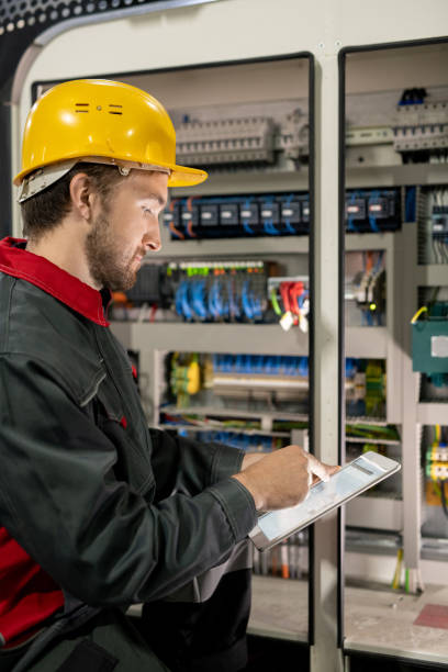 istock Young engineer in workwear and hardhat pointing at electronic sketch or scheme 1293598446