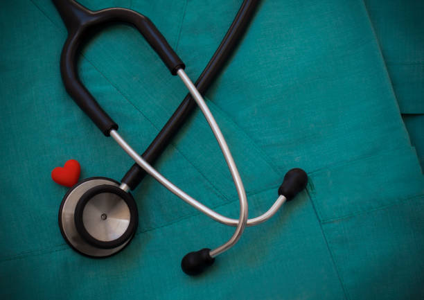 Stethoscope and red heart on green scrubs background Stethoscope and red heart on green scrubs background, top view. Medical objects. Cardiology concept. World health day and healthcare concept. Black stethoscope for doctor diagnostic coronavirus disease red medical scrubs stock pictures, royalty-free photos & images