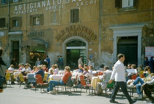 Rome, Italy, 1980. Ice cream parlor with a full terrace in a Roman square. Also: waiter and pedestrians.