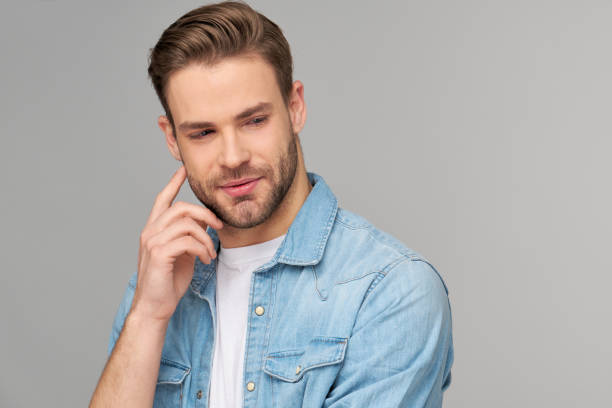 istock Portrait of young handsome caucasian man in jeans shirt over light background 1293600607