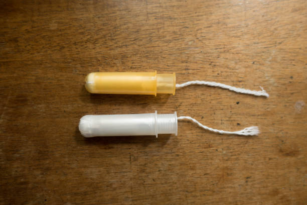 istock Two tampons with white and orange plastic applicators on wooden table 1293600757